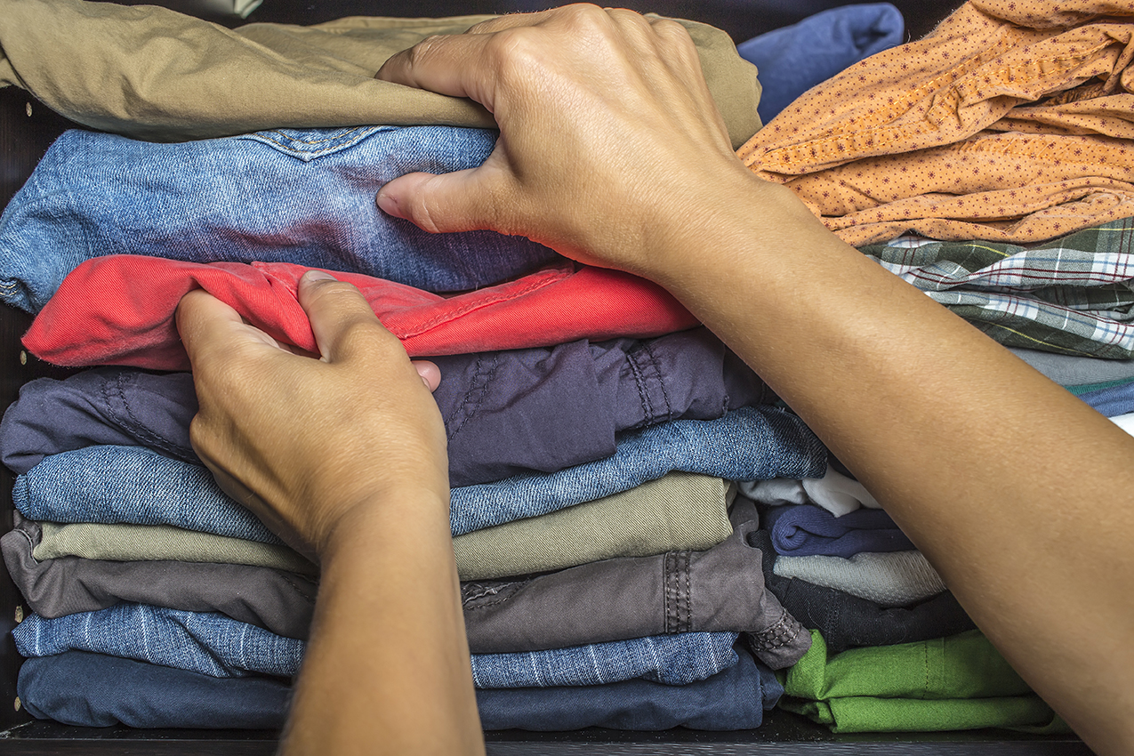 A man's arms choosing clothes from a pile